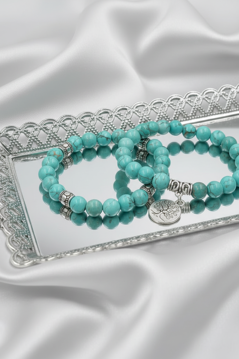Turquoise beaded bracelets on a decorative silver tray with a white satin background