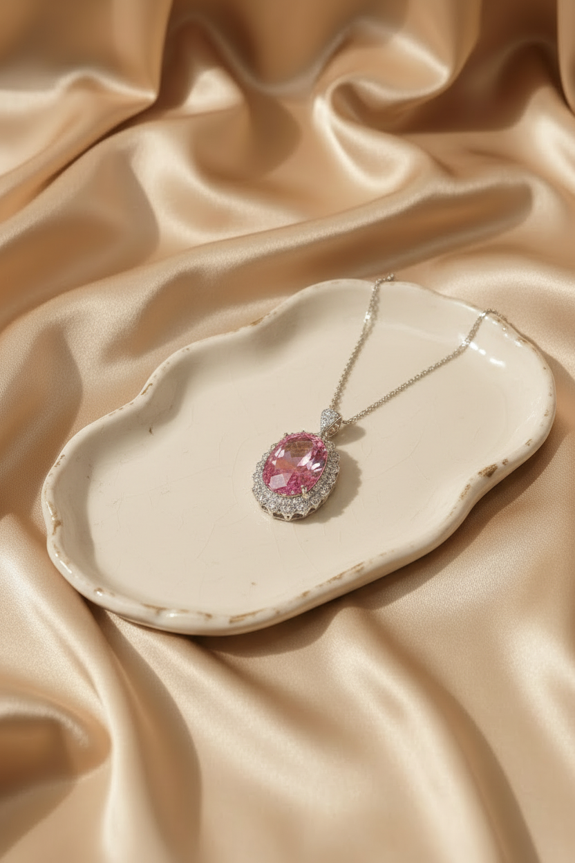 Pink gemstone necklace on a beige ceramic dish with a beige fabric background