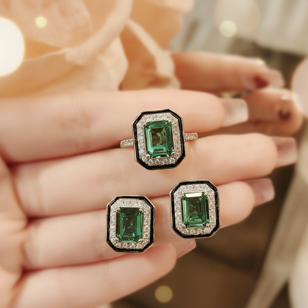 Emerald-cut gemstone earrings held on a hand with a blurred background