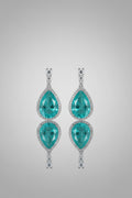Turquoise teardrop earrings with silver accents on a white and gray braided background