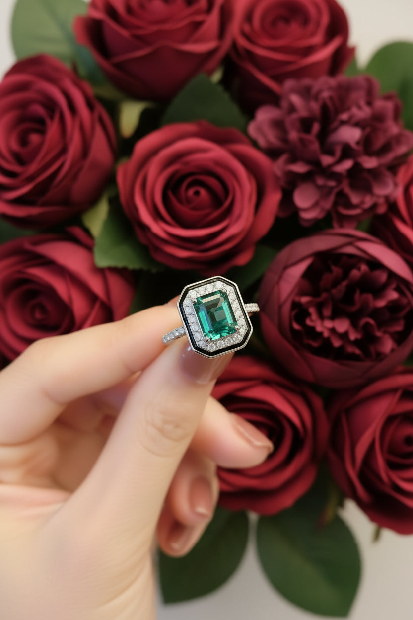 Close-up of a green gemstone ring with diamond accents held by a hand.