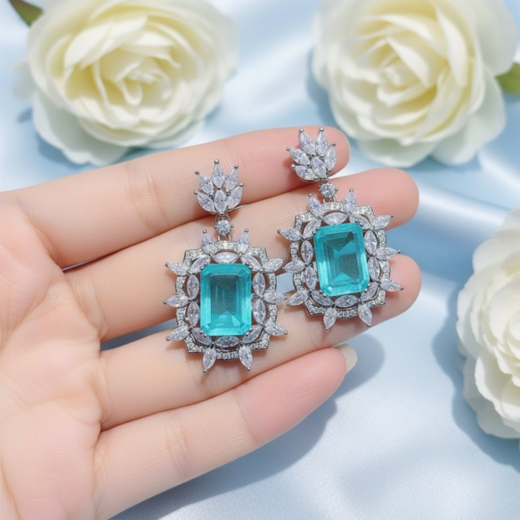 Earrings with turquoise gemstones and diamond-like stones on a hand