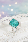 Ring with a green gemstone and silver band on a white surface